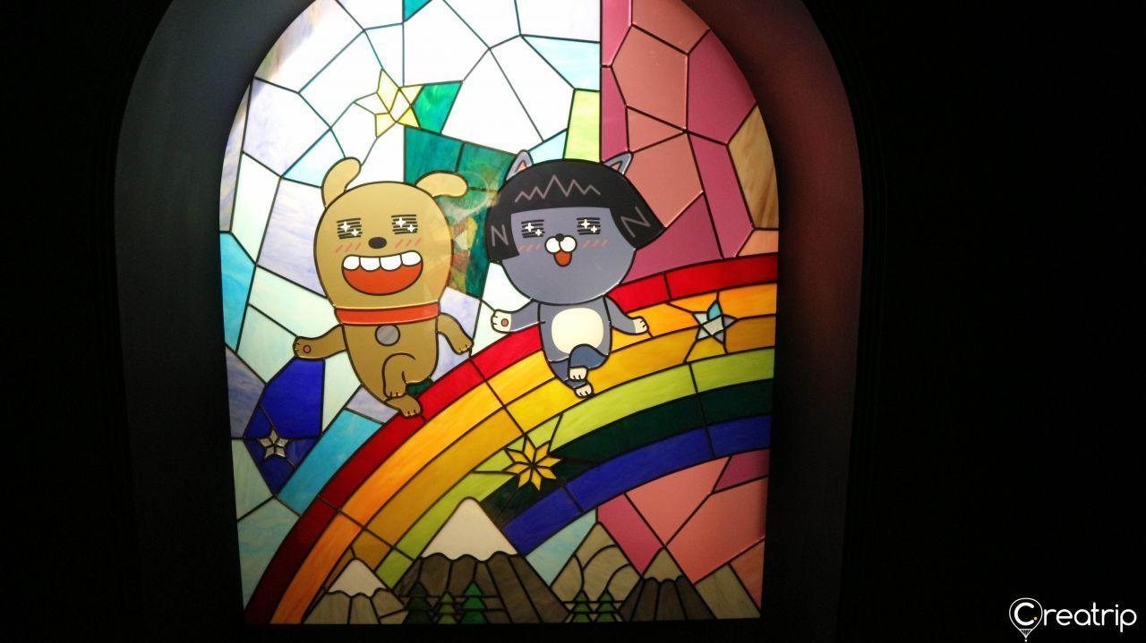 Vivid stained art panels with Kakao Friends imagery illuminating a museum room.