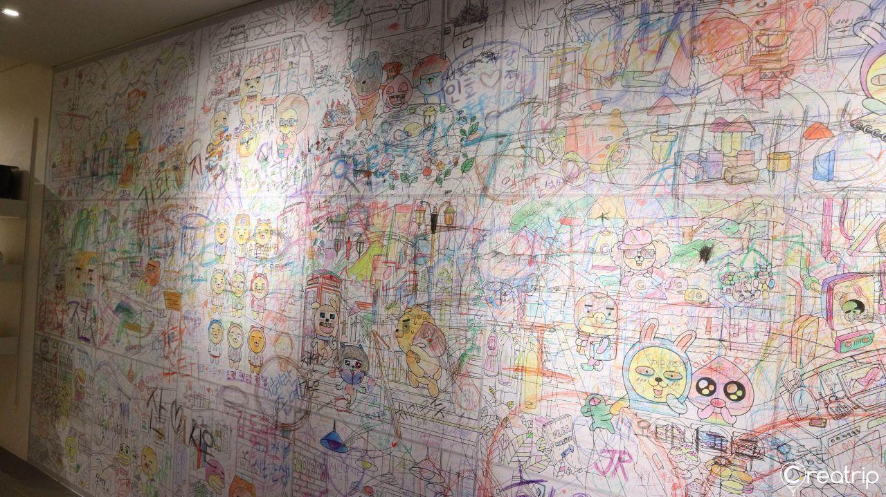 Interactive drawing area with visitors coloring on walls inside Kakao Friends museum.