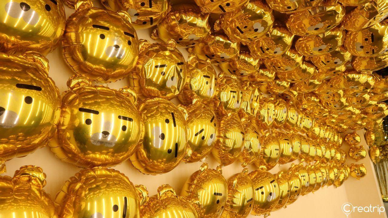 Close view of numerous golden balloons patterned with Ryan's face covering the area ceiling.