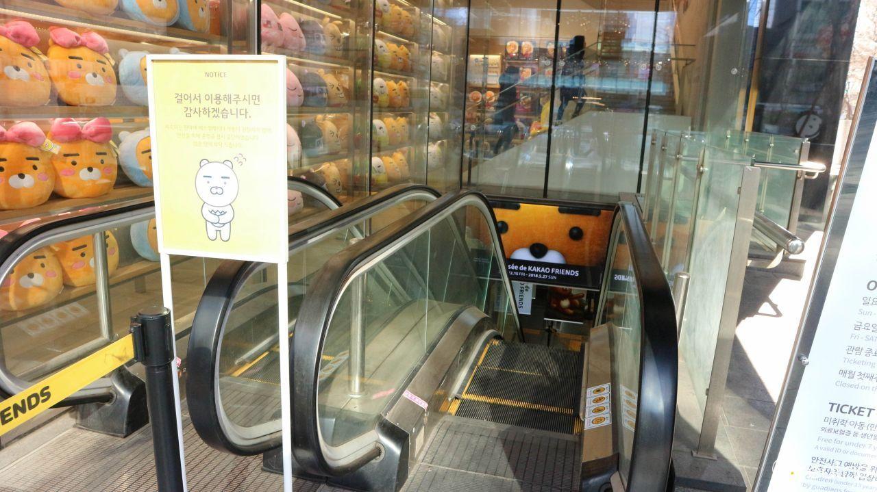 Escalator decorated with Kakao Friends plushies leading down to a lower level.