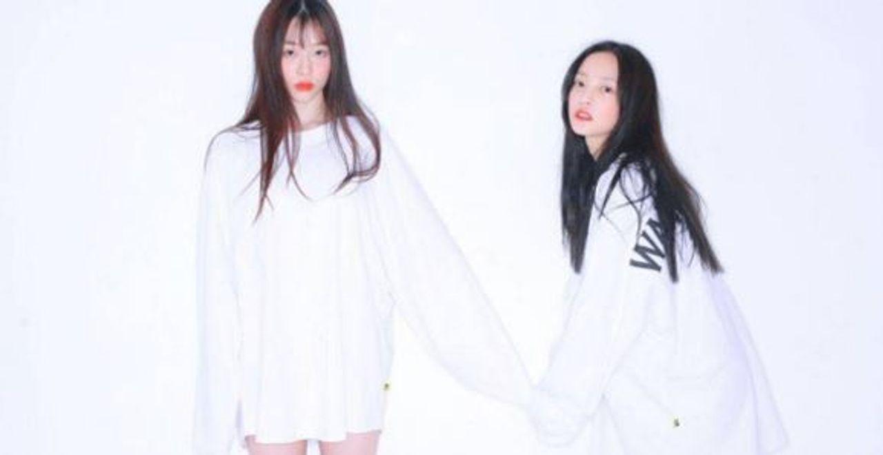 ภาพของสองคนในชุดสีขาวยืนจับมือกันในชุดคลุมสีขาวยาว