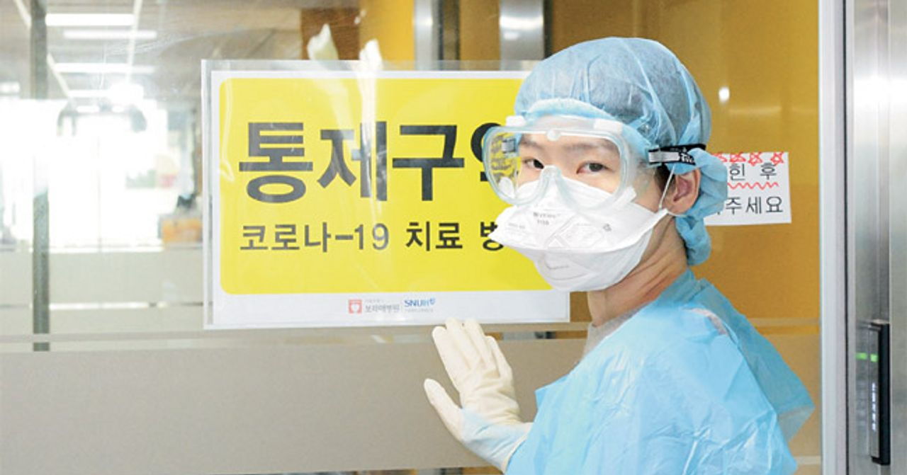 醫護人員站在貼有“COVID-19治療病房”標誌的門口，正在查看情況。