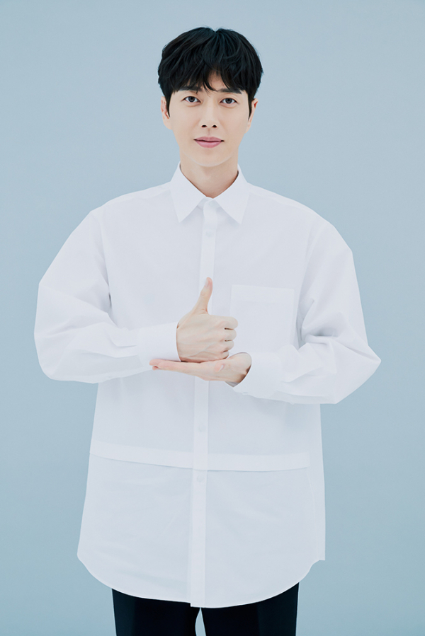 身穿白襯衫的男士在工作室背景中展示感謝手勢，參與韓國抗疫活動。