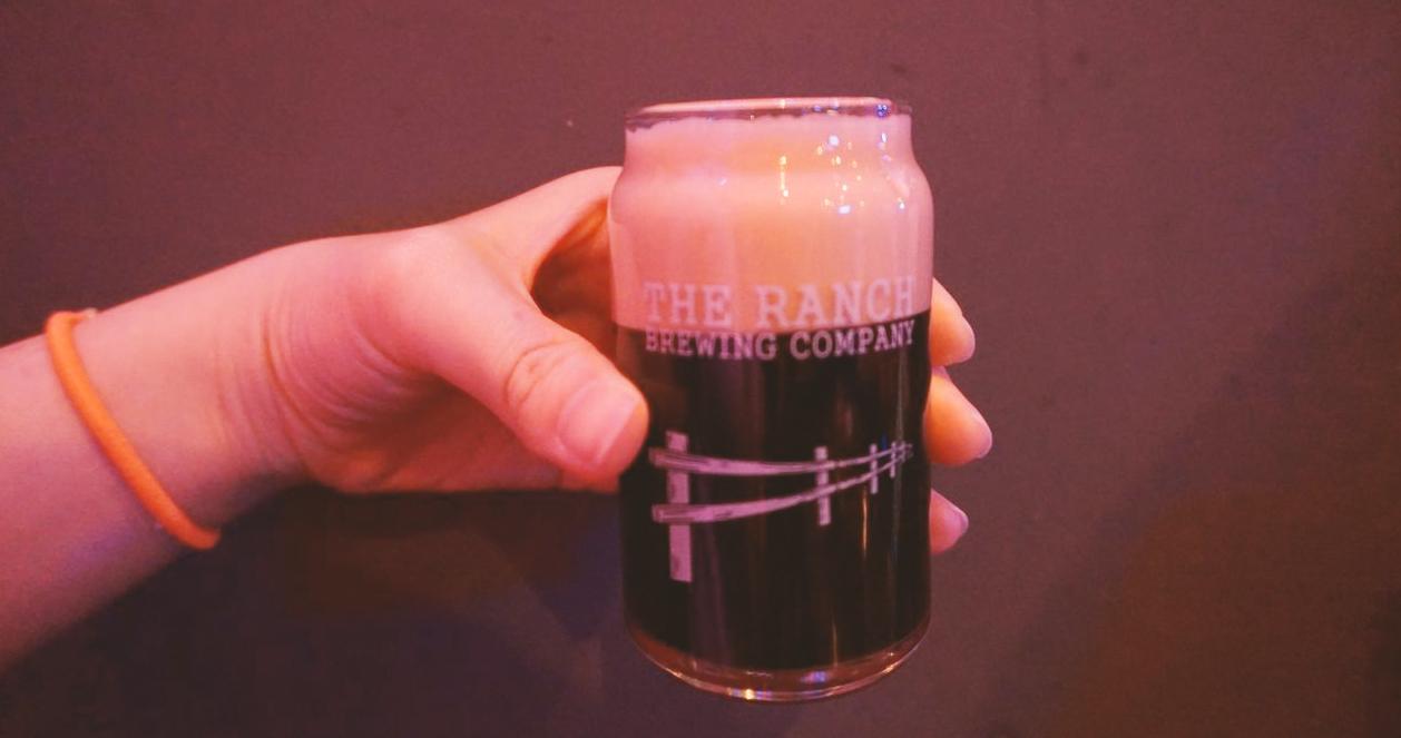 Ly bia đen với bọt nhiều từ The Ranch Brewing Company, nổi bật trong không gian quán Beer Duckhu, Seoul.