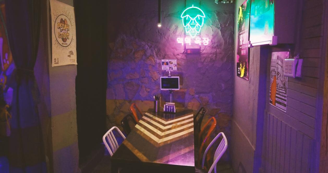Góc nhìn tối với đèn neon sáng tại bàn ăn trong Beer Duckhu x The Ranch Brewing, một quán bia và pizza tại Euljiro, Seoul.