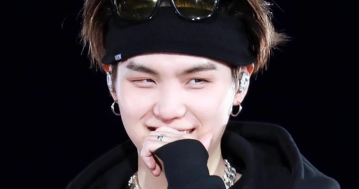 SUGA của BTS trên sân khấu biểu diễn, mặc trang phục phong cách và đeo kính mát