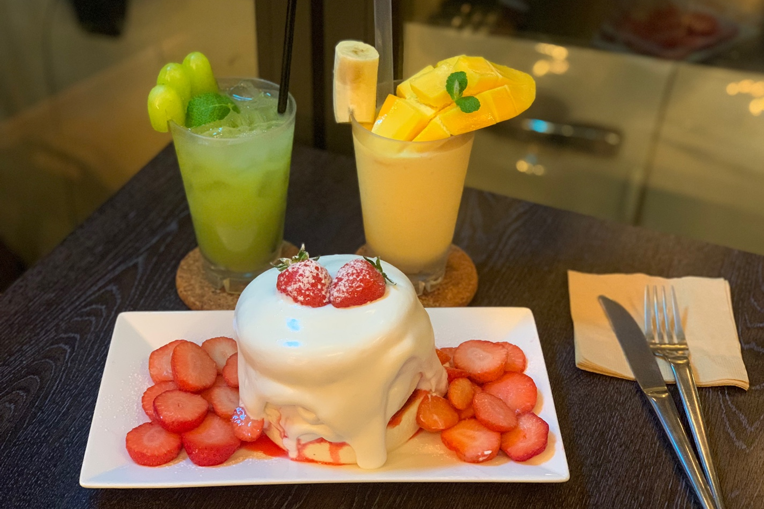 신선한 청포도 주스와 망고 요구르트 스무디, 딸기 수플레 팬케이크와 함께 세련된 프레젠테이션.