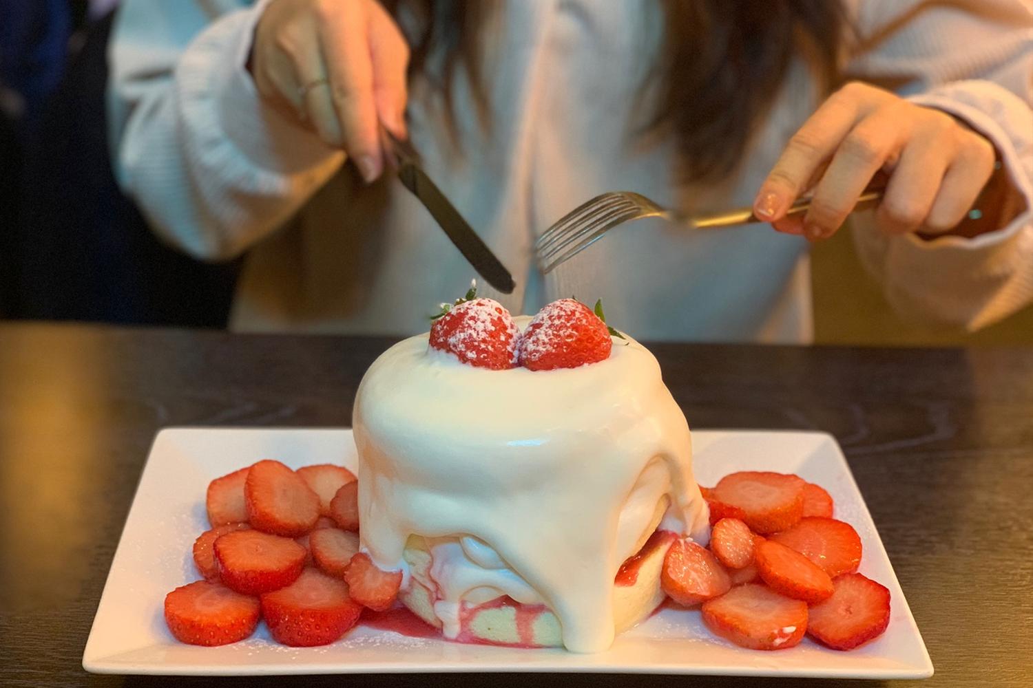 딸기 수플레 팬케이크, 두껍고 푹신한 팬케이크에 신선한 딸기와 생크림이 듬뿍 얹어져 있음.