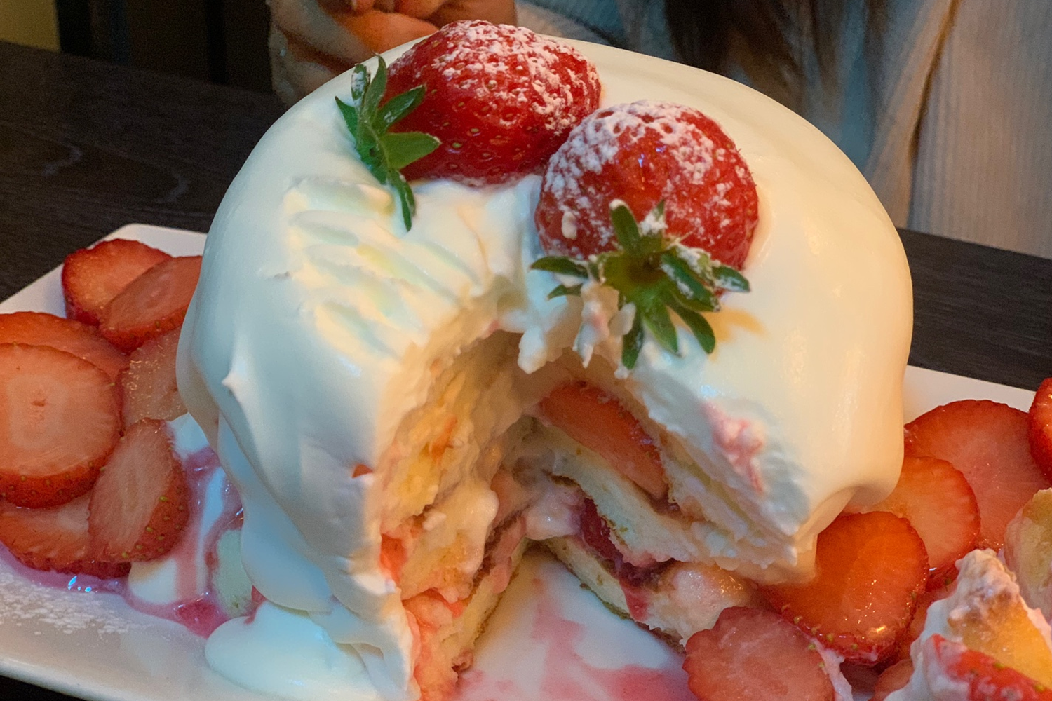 상큼한 딸기 수플레 팬케이크의 단면, 두껍고 부드러운 팬케이크가 내부에 딸기 조각과 크림을 포함하고 있음.