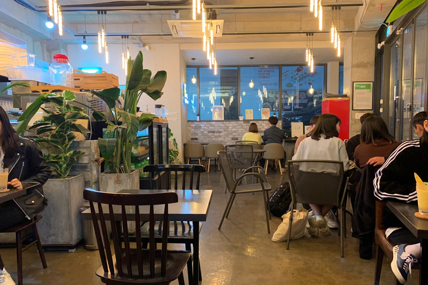 카페 내부 전경, 젊은 학생들이 모여 있음을 보여주는 테이블과 의자가 배치된 깔끔한 인테리어.