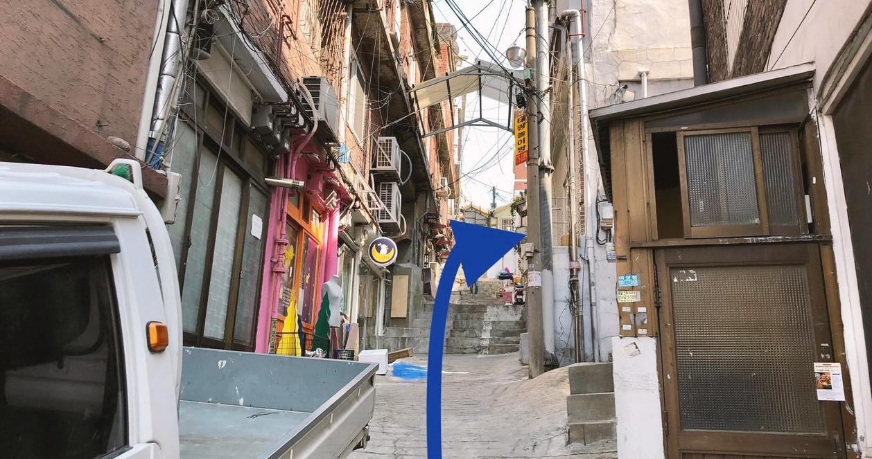 Ngõ nhỏ bên cạnh Seven Hair Shop với bảng hiệu màu xanh nổi bật, một phần của hành trình khám phá khu dân cư ẩn mình tại Itaewon, Seoul.