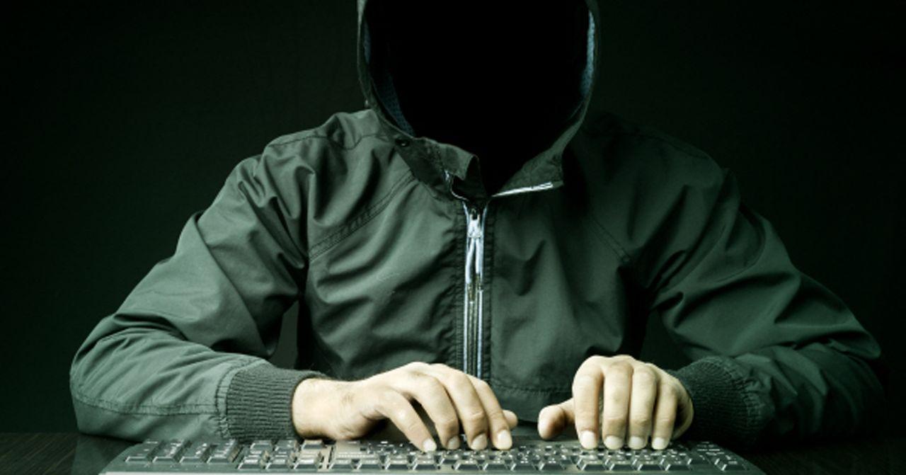 ชายหนุ่มอายุ 16 ปี ในเสื้อฮู้ดสีเขียว นั่งอยู่หน้าจอคอมพิวเตอร์ กำลังพิมพ์ที่แป้นพิมพ์ สร้างบรรยากาศของการทำกิจกรรมออนไลน์หรือการแฮ็กเกอร์อย่างเงียบๆ ด้วยไฟล้อมรอบตัวในห้องมืด