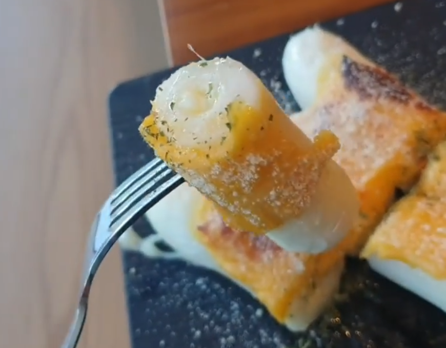 チーズカレ餅をフォークで刺した韓国のデザート、チーズがたっぷりかかった韓国菓子画像