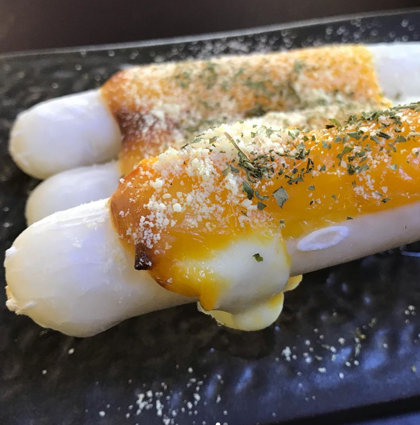 チーズがたっぷり乗った韓国式餅、カラフルなスナック、チーズカレ餅のクローズアップ画像