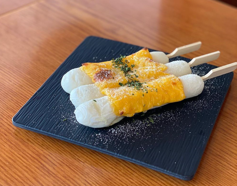 ソルビンの2対のチーズカレ餅が黒い皿に並んだ韓国デザートの画像