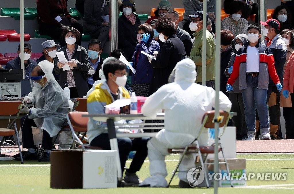 新冠病毒檢測現場，市民排隊等待接受檢測，穿上防護裝備的工作人員正在檢查紙質文件。