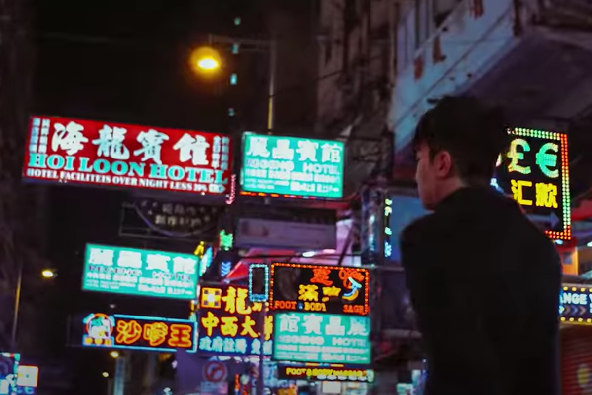 香港旺角夜市的霓虹燈牌及攤檔背景，行走中的年輕人