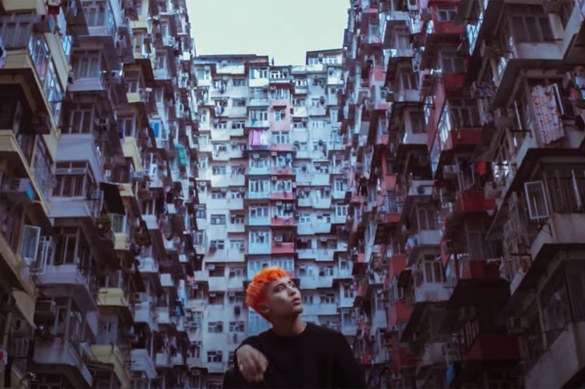 香港鰂魚湧怪獸大廈前漫步的年輕人，背後是密集的住宅樓