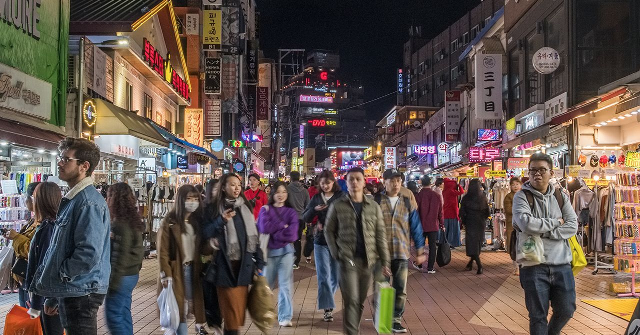 ภาพถนนคนเดินในโซลที่มีผู้คนเยอะมากในยามค่ำคืน ระหว่างที่เดินชมร้านค้าและอาหารที่หลากหลายซึ่งสามารถดึงดูดนักท่องเที่ยวด้วยความสดใสและความคึกคัก