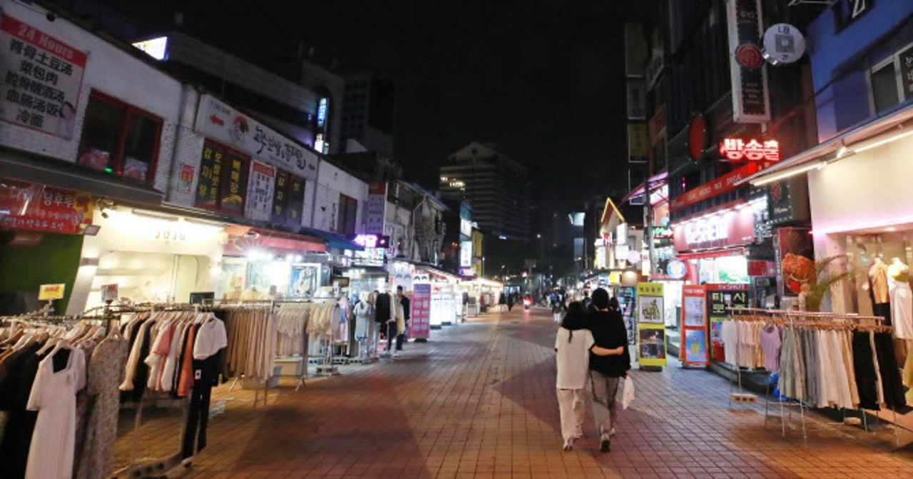 弘大酒吧街夜晚景象，商店和建築物攤位排成一列，街道上的行人提供了韓國夜生活的視角。