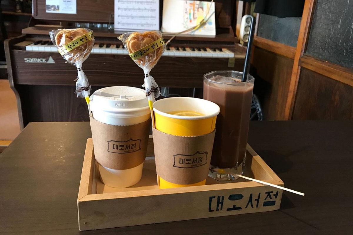 ถ้วยเครื่องดื่มและขนมเล็ก ๆ ในแดโอ ซอจอม คาเฟ่ที่มีบรรยากาศอบอุ่นที่มุมหนึ่งของร้าน