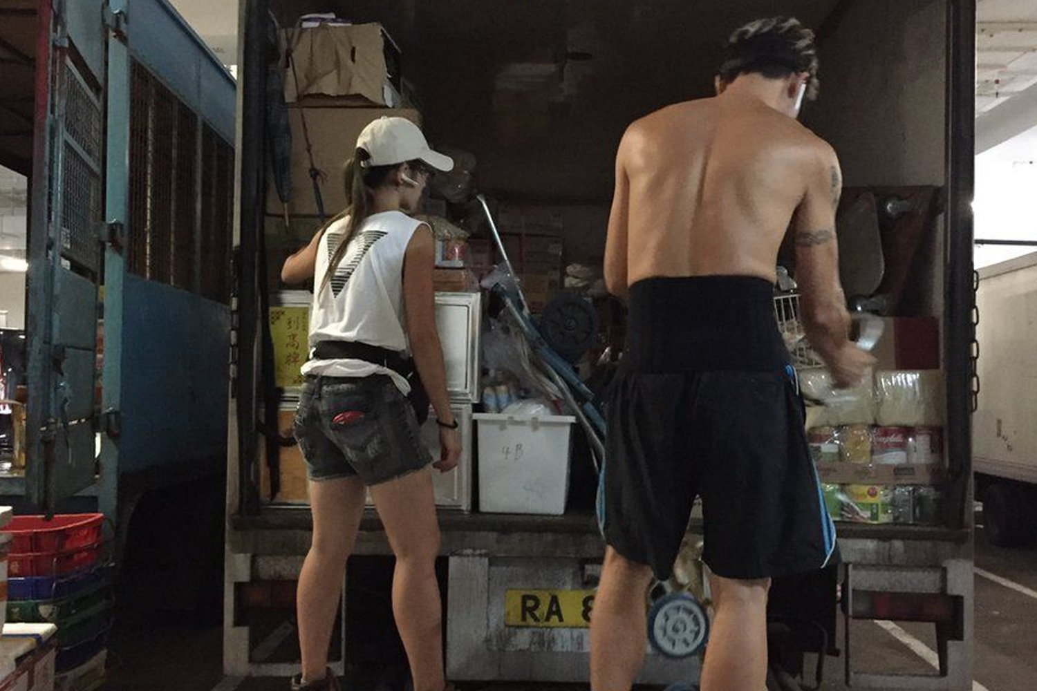 正在搬運物品的工人，他們在夏天穿著清涼，顯示出香港炎熱天氣下的一種工作狀態。