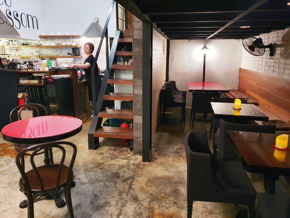 Interior view of Choco Blossom in Sinchon featuring cozy seating arrangements with red and wooden furniture, creating a warm and inviting atmosphere.