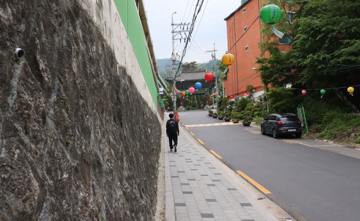 Pengunjung kuil yang mengenakan pakaian tradisional sedang menikmati pemandangan alam yang tenang di sekitar Hwagyesa.