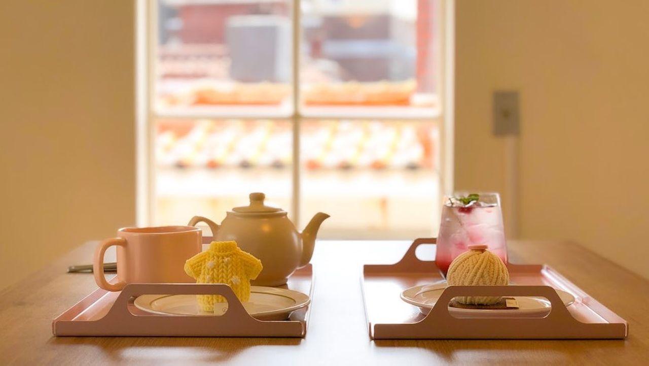 เครื่องดื่มและหม้อชาในคาเฟ่ที่ตกแต่งอย่างอบอุ่นในย่านอิแทวอน, พร้อมถ้วยสีชมพูและเครื่องดื่มสีแดงในถาดไม้.