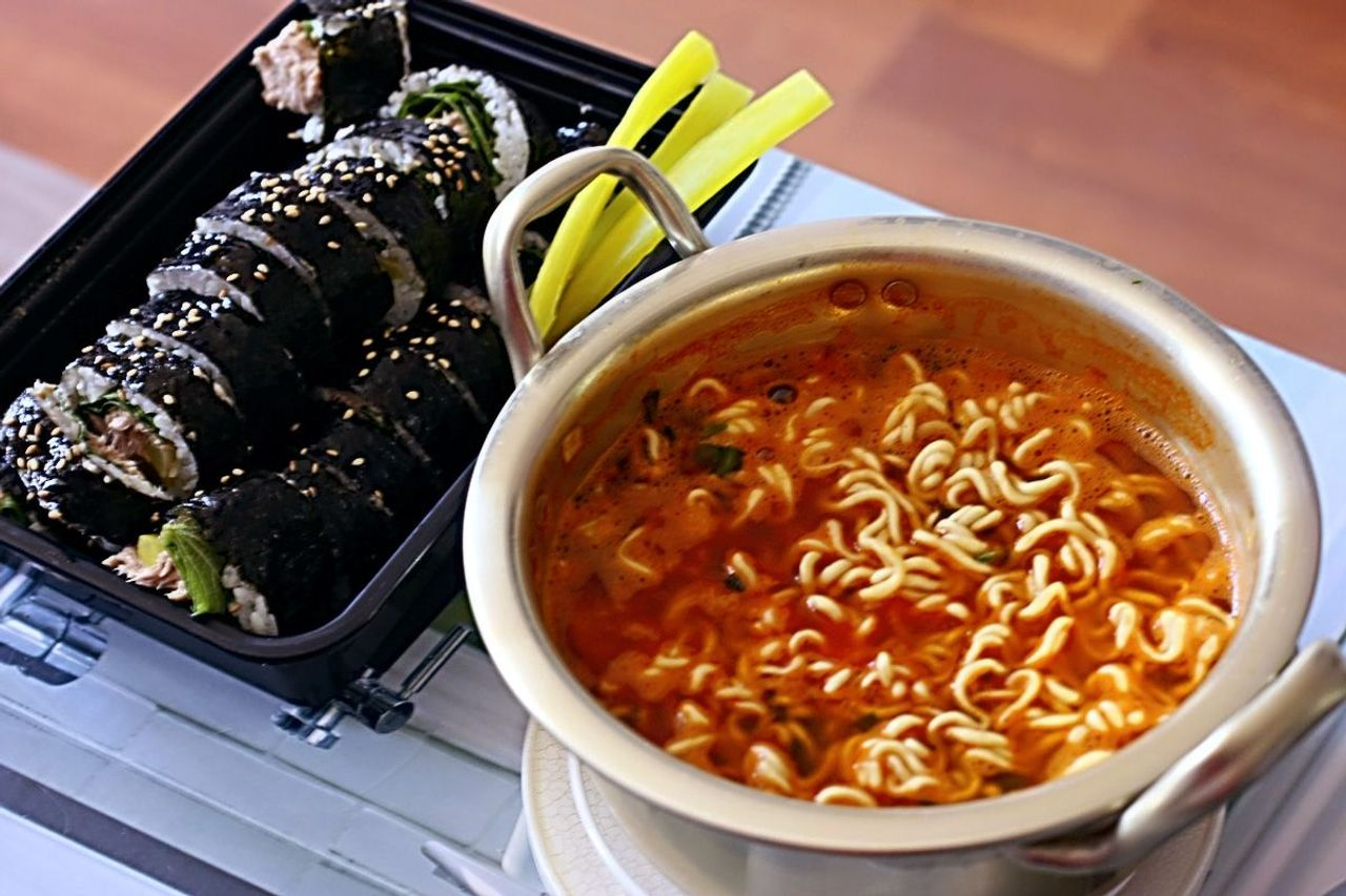 一張韓國食物的圖片，展示了一碗韓式拉麵和紫菜包飯，象徵著韓國人的日常餐食。