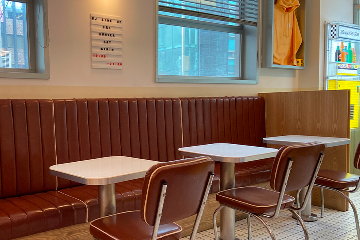 The Famous Burger新沙店的座位展示，復古皮革座椅和明亮的窗户。」