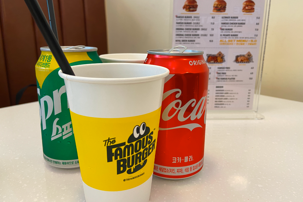 The Famous Burger店內的飲品展示，包含可樂和雪碧的罐裝飲料。