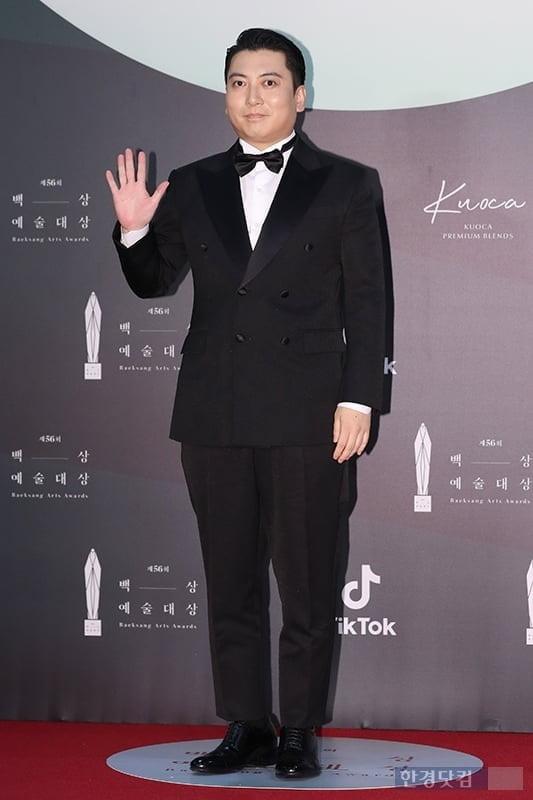 第56回百想芸術大賞において、映画『寄生虫』のパク・ミョンフンがレッドカーペットで登場したシーン。フォーマルなスーツ姿で手を振り、注目を集めている。