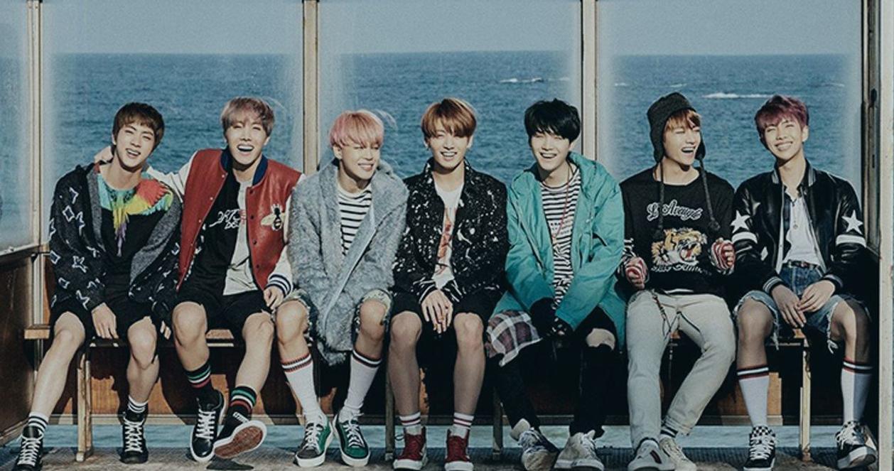 Các thành viên BTS trong trang phục bình thường ngồi bên biển.