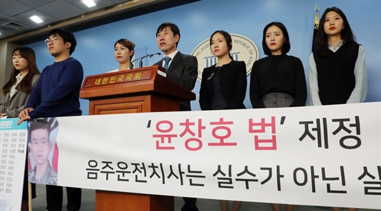 尹昌浩法立法的新聞活動場景,由一羣法律制定者正在發表聲明,強調法律修訂的重要性。