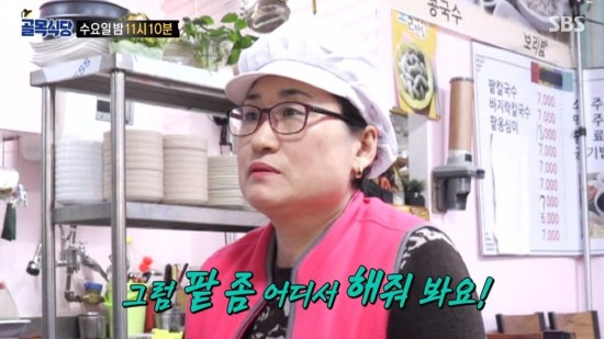 在餐廳裡的廚師，背景是展示的菜單和廚具。