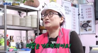 在餐廳裡正在工作的廚師，背後是顯示菜單的背景。