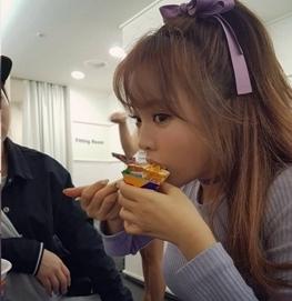 穿著紫色蝴蝶結的女孩正在餐廳用餐，背景有其他顧客。