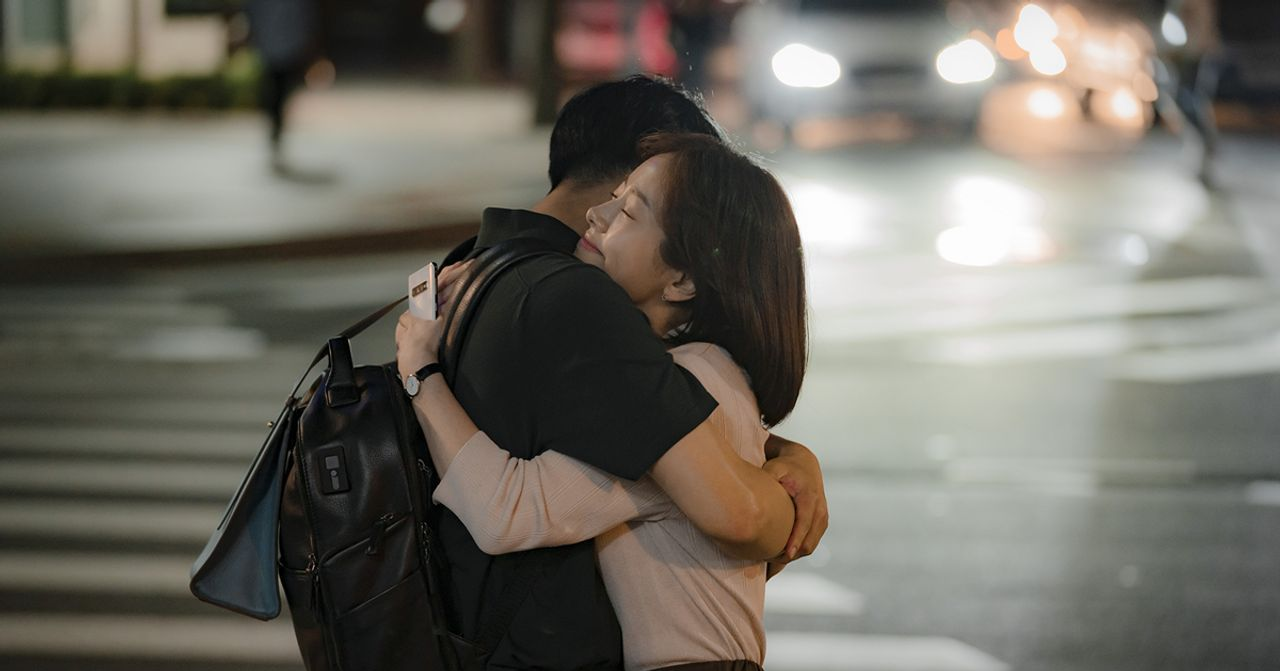 韓劇中街頭擁抱的情侶，背景有車燈和行人。
