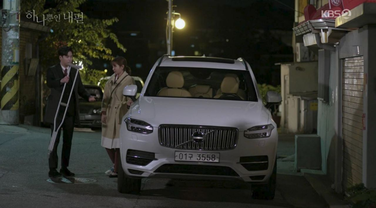 夜間街道旁停著一輛白色的汽車，背景是韓國的夜景。