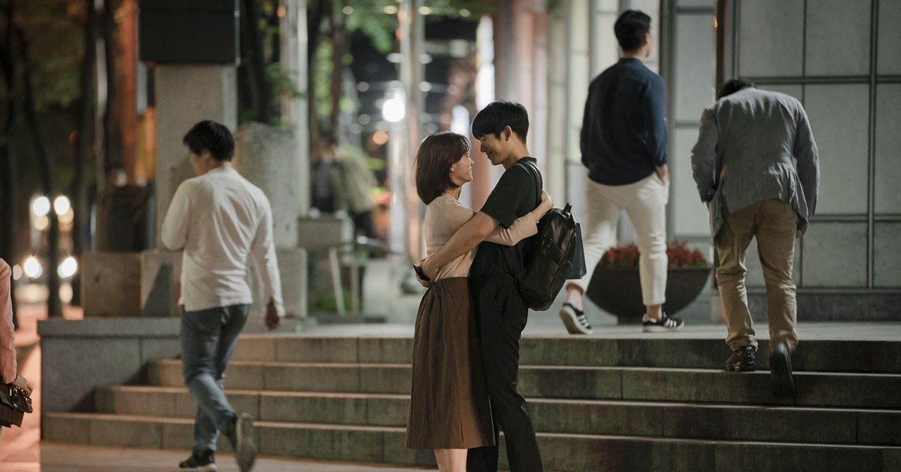 夜晚街道上兩人擁抱的韓劇場景，背景是城市的街燈閃爍。