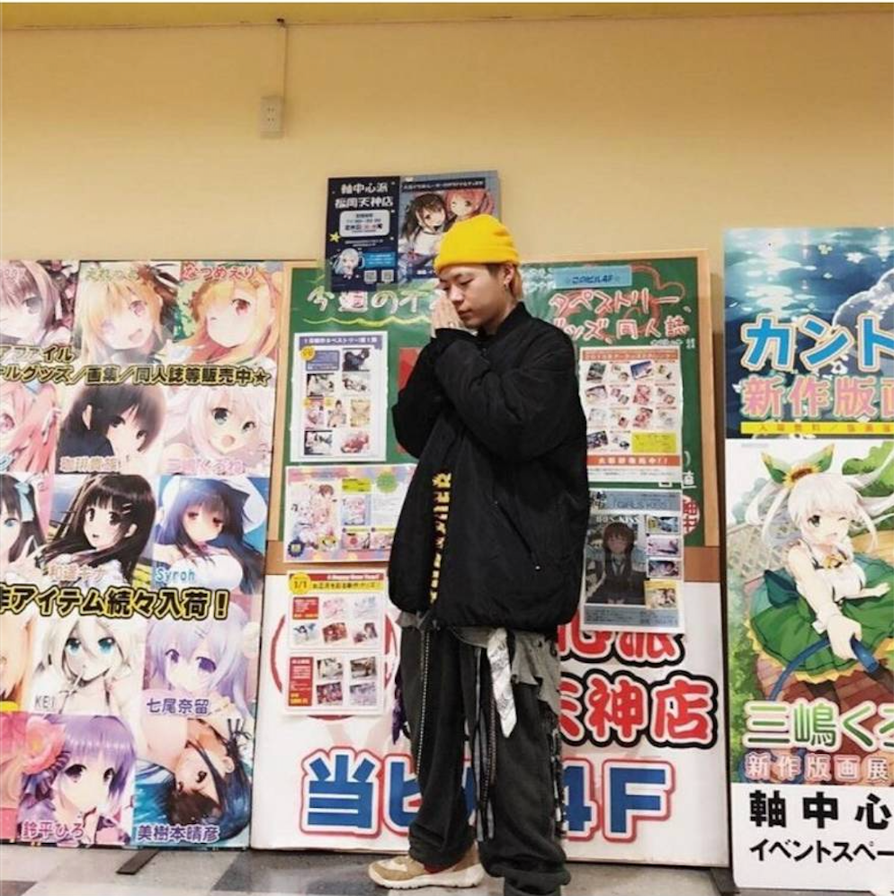 丁德米粒風格穿搭，展現寬鬆多層次搭配和鮮明的街頭感，背景是漫畫海報牆。