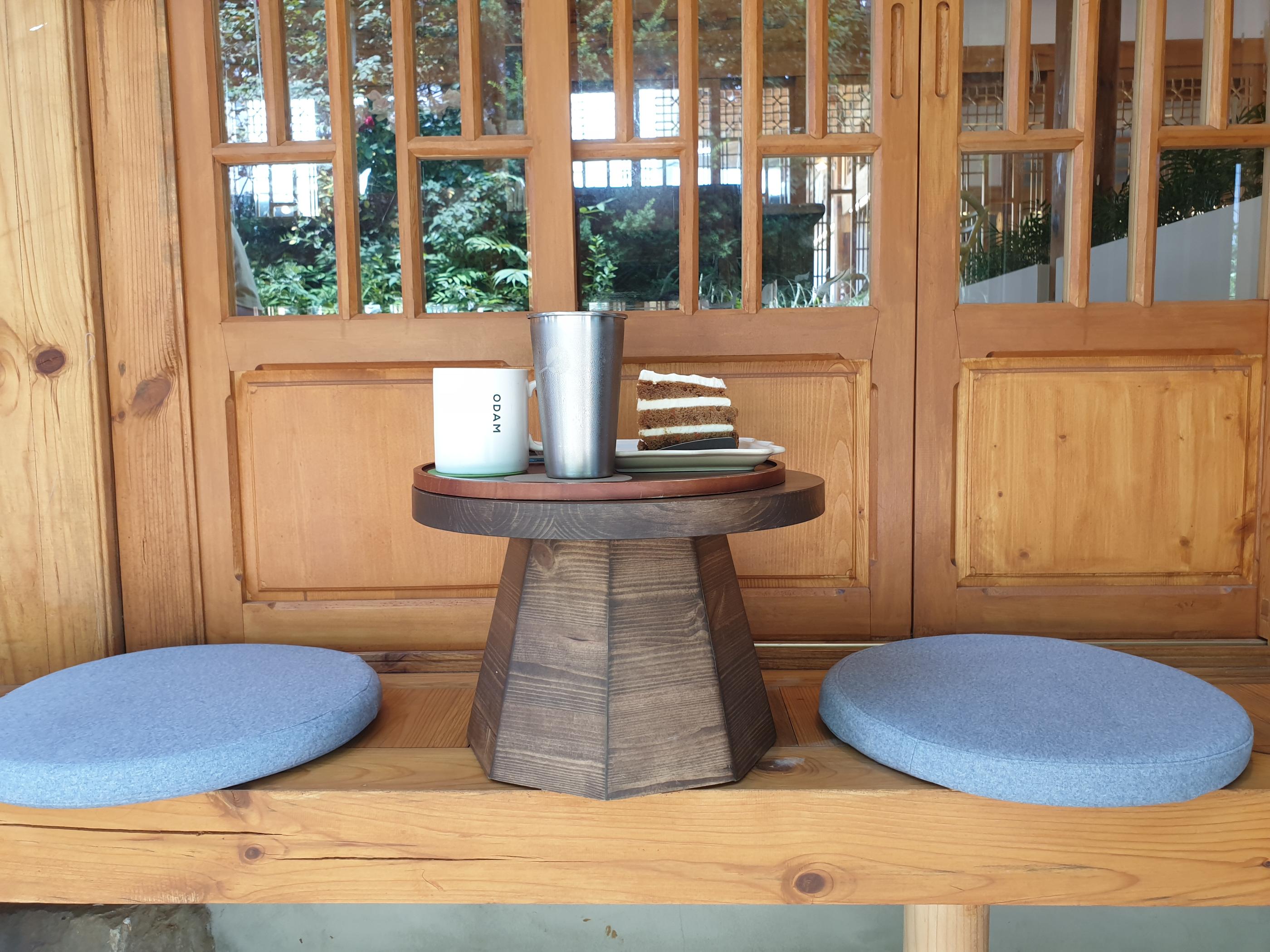 韓屋カフェの座敷タイプの座席に並んだ三つのゴム靴とキャロットケーキセットのテーブルディスプレイ。