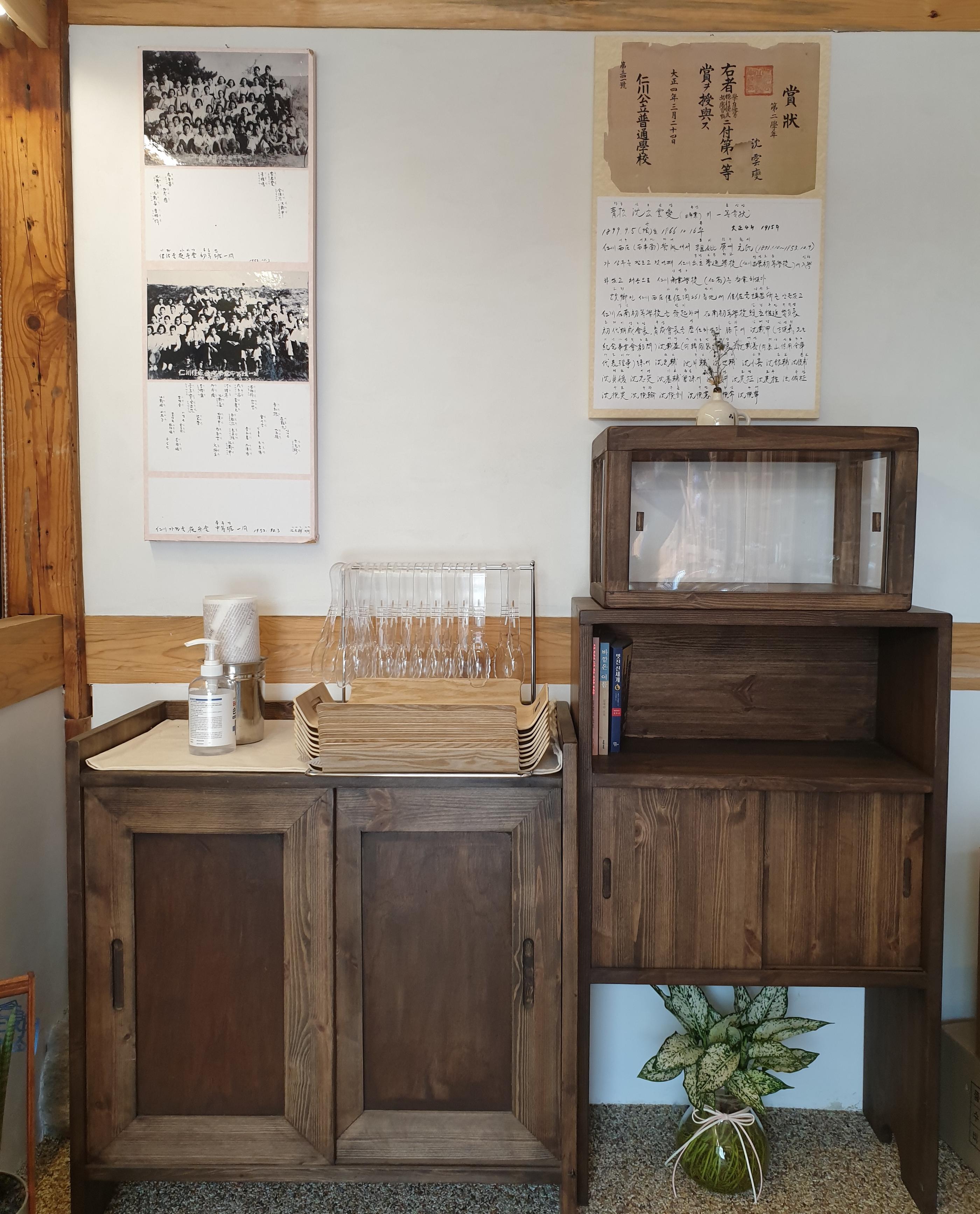 歴史ある韓屋カフェの内部の木製キャビネットと壁の額縁に入りの写真と説明書き。