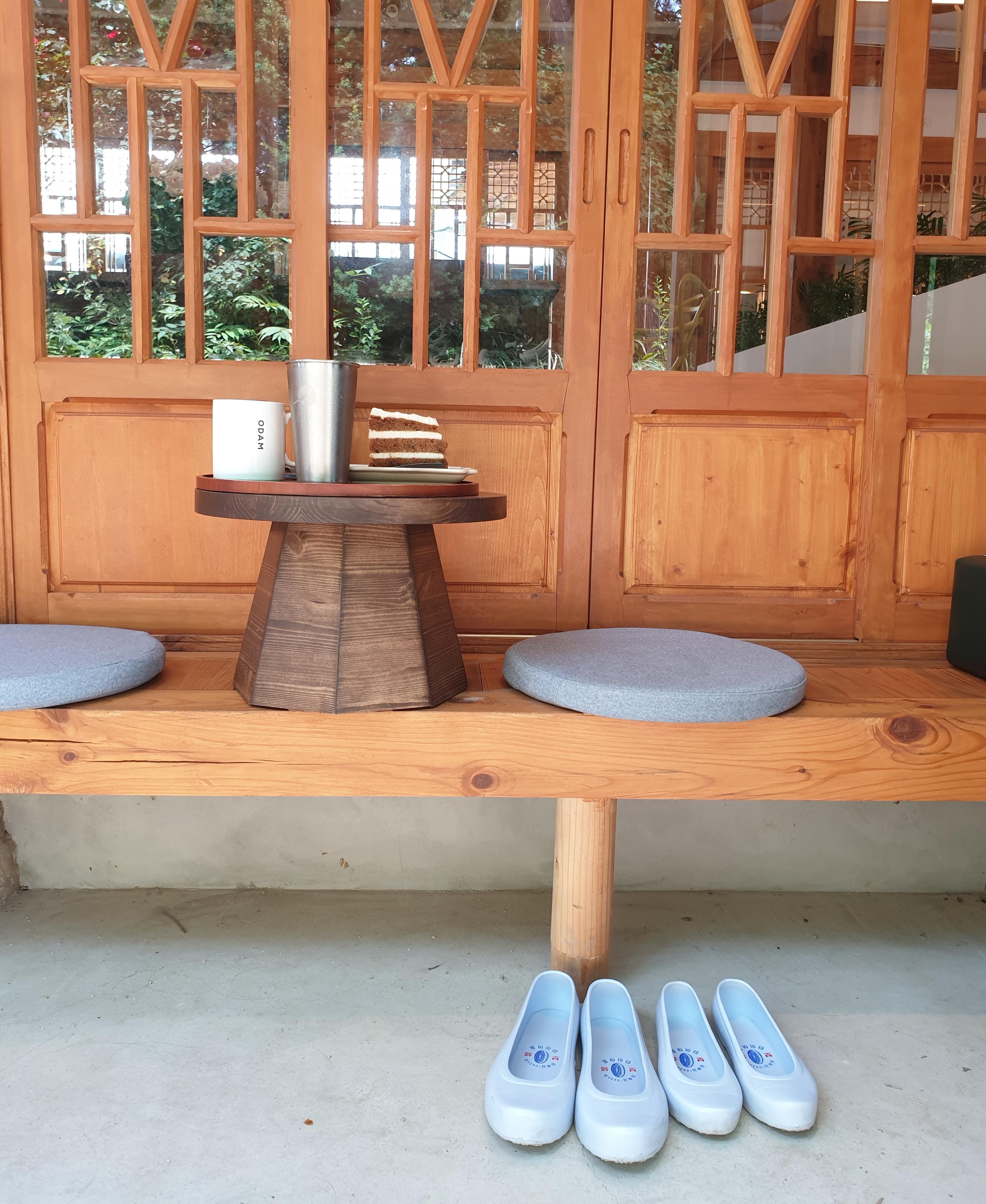 テーブルの上に置かれたホットコーヒーとキャロットケーキ、冷たい飲み物と韓屋カフェの伝統的な雰囲気を垣間見る。