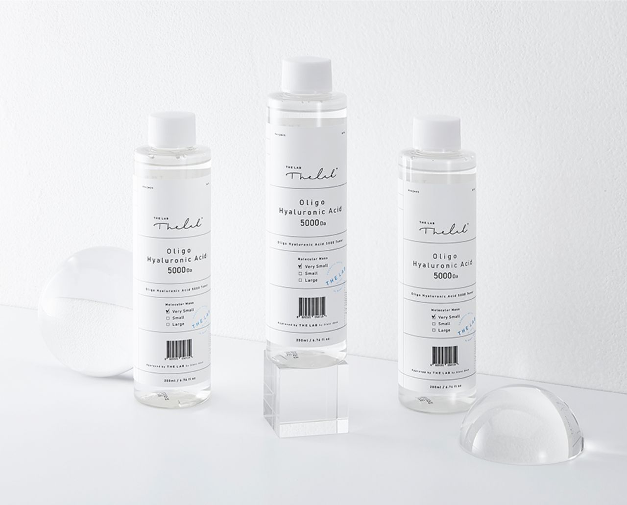 THE LAB by blanc doux 的微小分子玻尿酸化妝水，它在背景是白色牆壁，旁邊有幾何形狀的透明道具，讓產品外觀更顯雅緻。