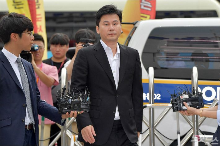 男士走出建築外，背景為記者和攝影機，拍攝場景似乎在法院或公司外面。