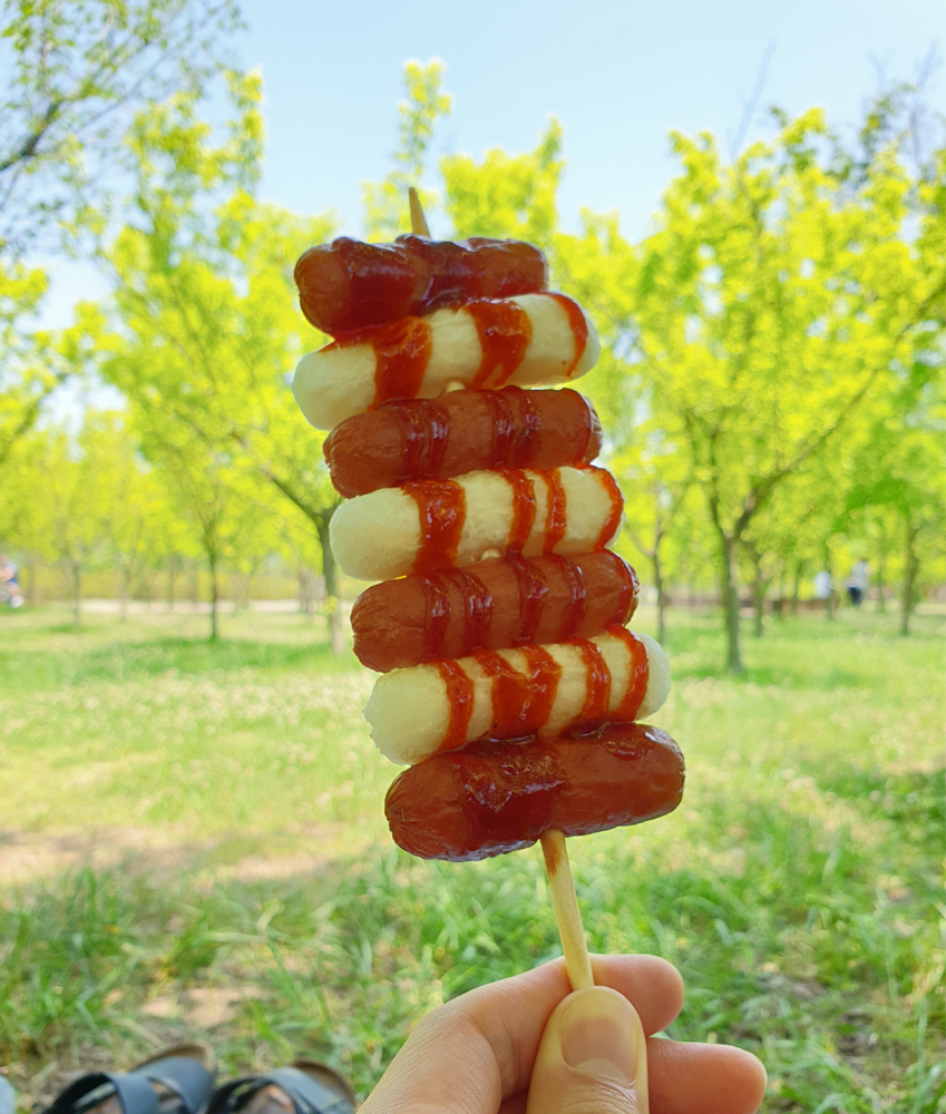 手持香酥的韩国年糕香肠串，享受户外悠闲时光