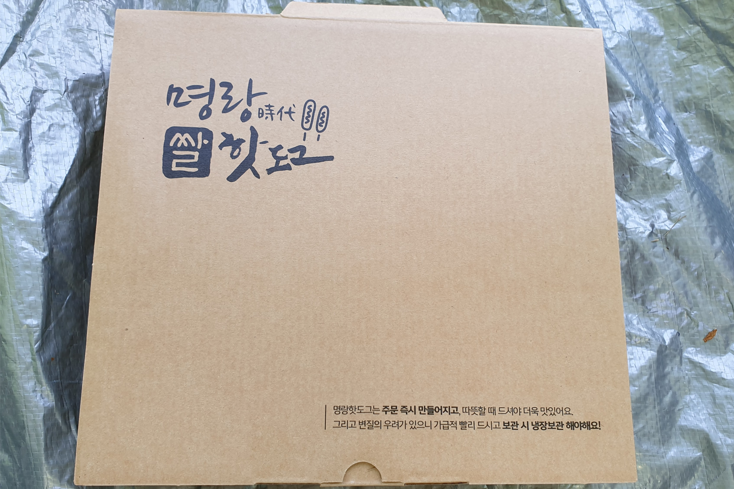 明朗热狗外卖纸盒，盒子上印有品牌标识和信息