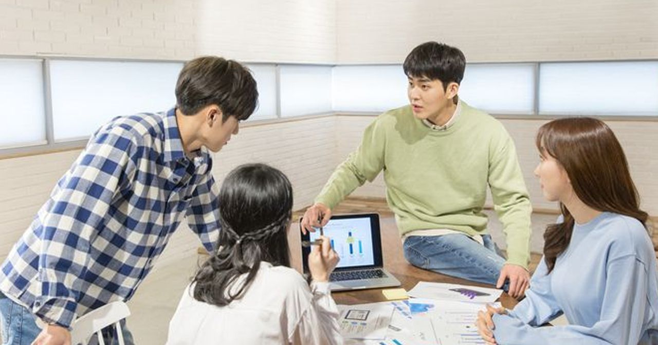 韓國年輕人在室內開會，交流討論，桌上有筆記本電腦和文件。